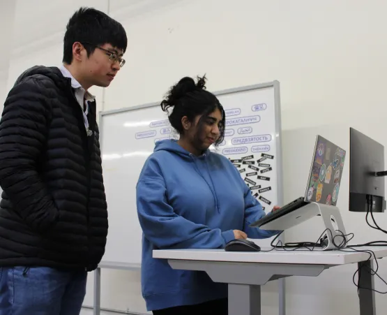 Two students looking at laptop on standing desk